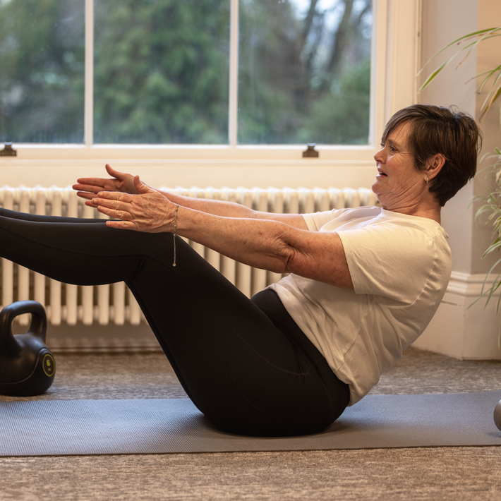 Woman exercising on a mat in a home setting with a window in the background